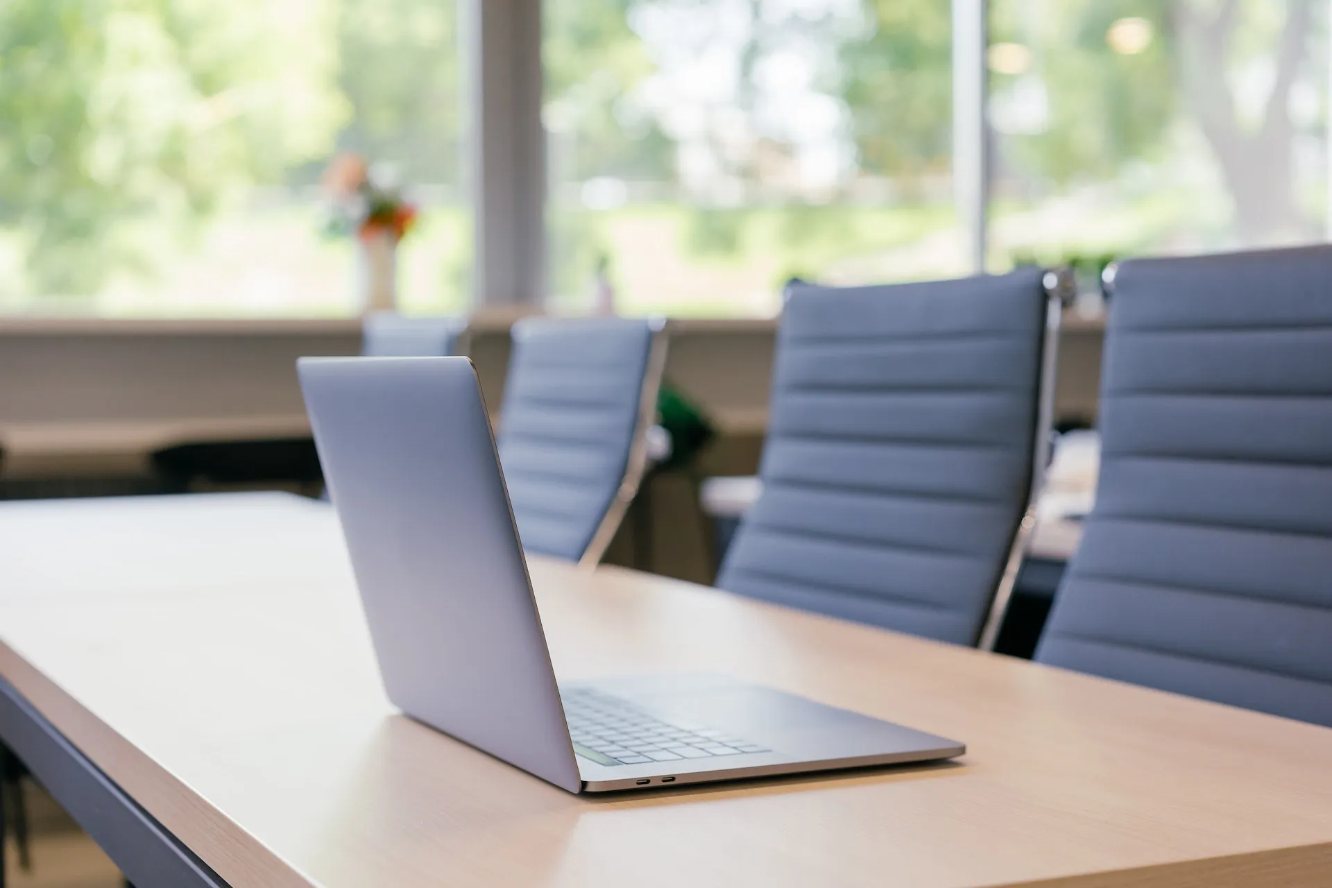 a laptop on a table with chairs in the background
